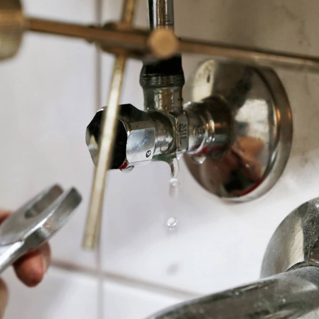 Water leaking from shutoff valve connection under sink requiring plumbing repair